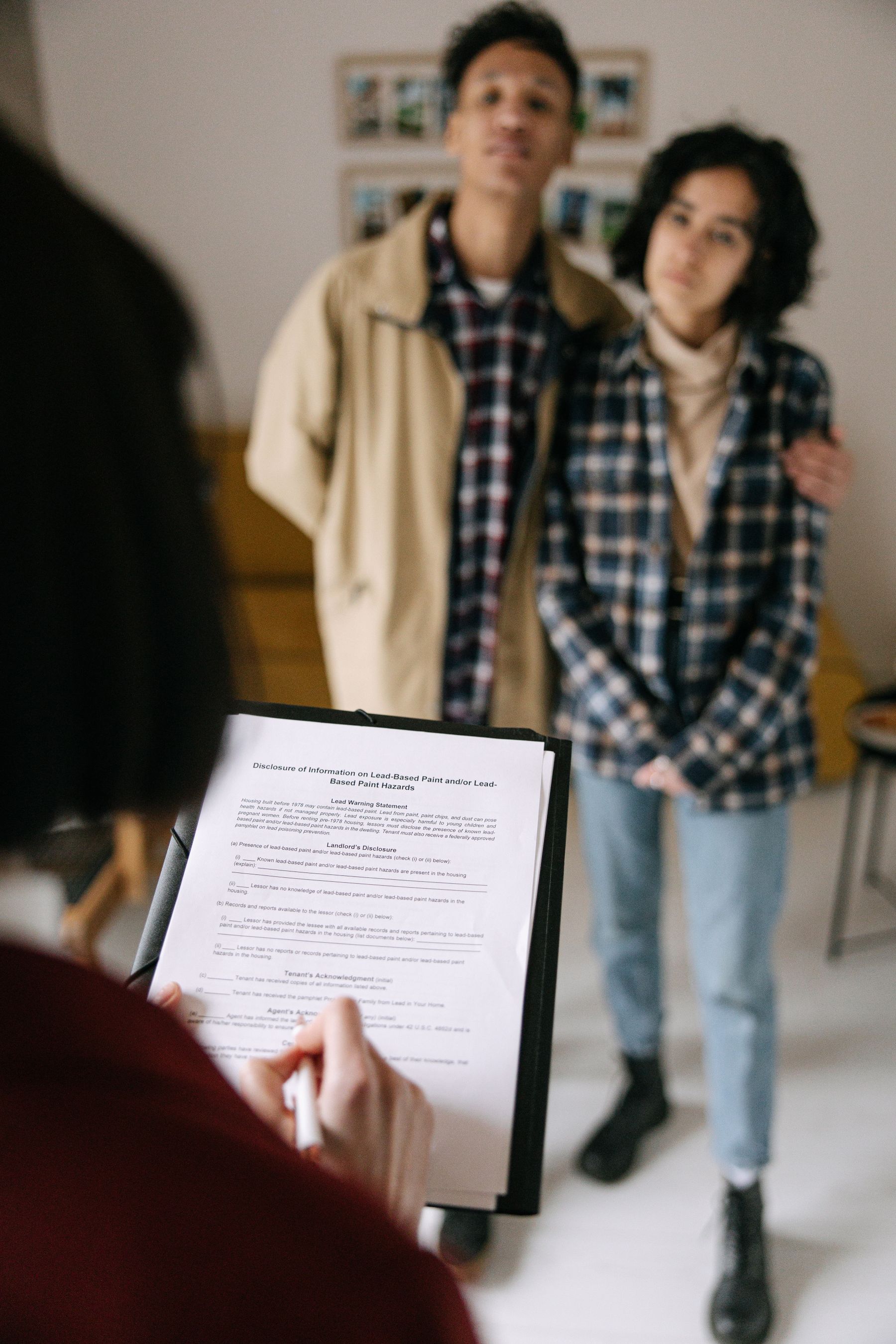 Una joven pareja revisa documentos inmobiliarios con un agente